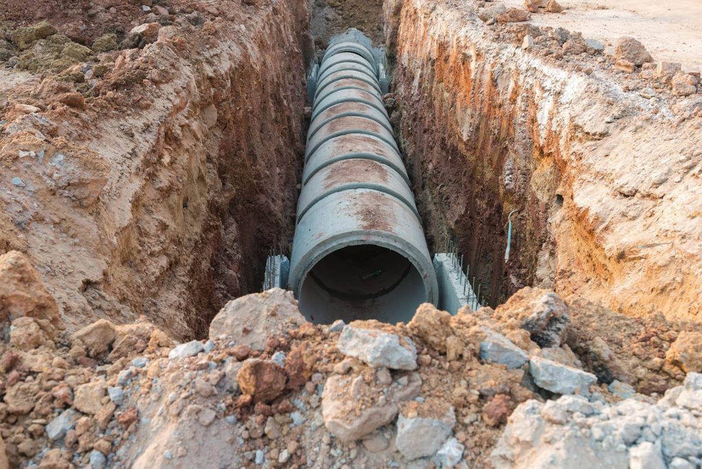 Row of concrete drainage pipe under earth near the construction